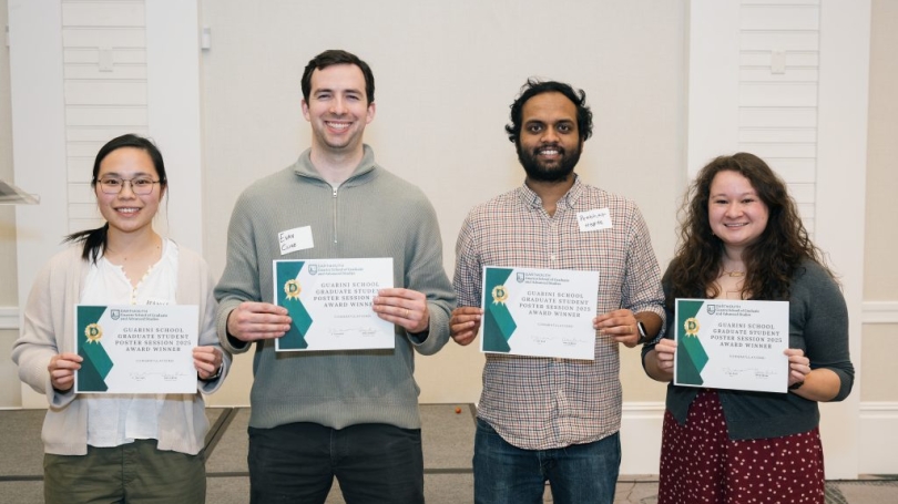 four graduate students smiling and holding up award certificates