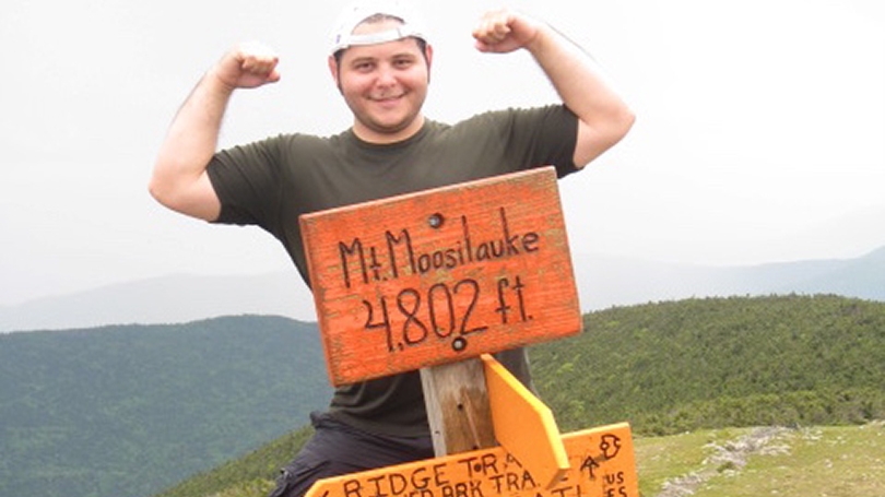 A student poses at the top of Mount Moosilauke.