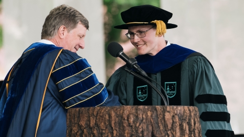 Two men in graduation regalia shaking hands