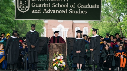 students in graduation regalia receiving awards on a stage.