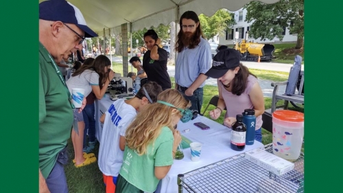 families and students engage in science activities on the green