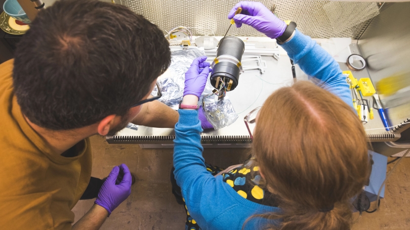 Jules Van Irsel GR, holds the stand while Magnali a Moses GR screws the Petite Ion Probe Bob onto it. The stand holds up the Bob during space simulations in the ELEPHANT (Experimental Low Energy Plasma for Hemispherical Analyzer Nominal Testing) Vacuum Ch