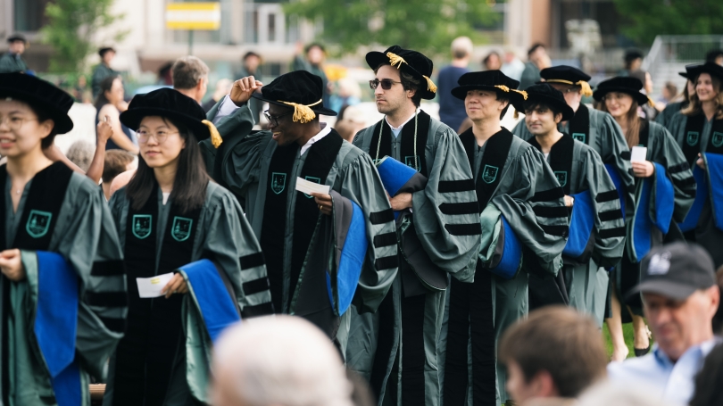 Doctoral students wearing academic regalia marching during Investiture.