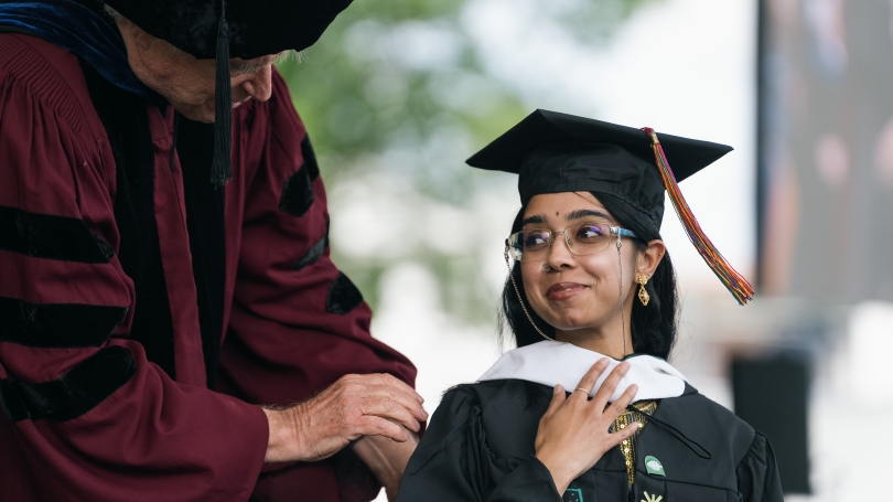 a man in regalia hooding a newly graduated masters student.