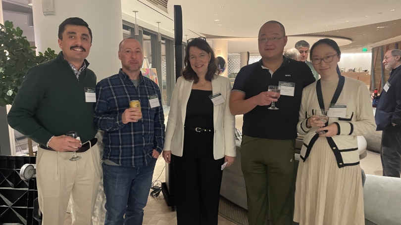 Five people standing in an event space smiling and holding glasses