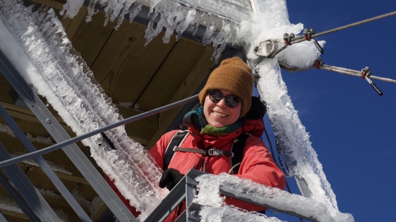 woman in sunglasses standing on an icy fire tower in the winter